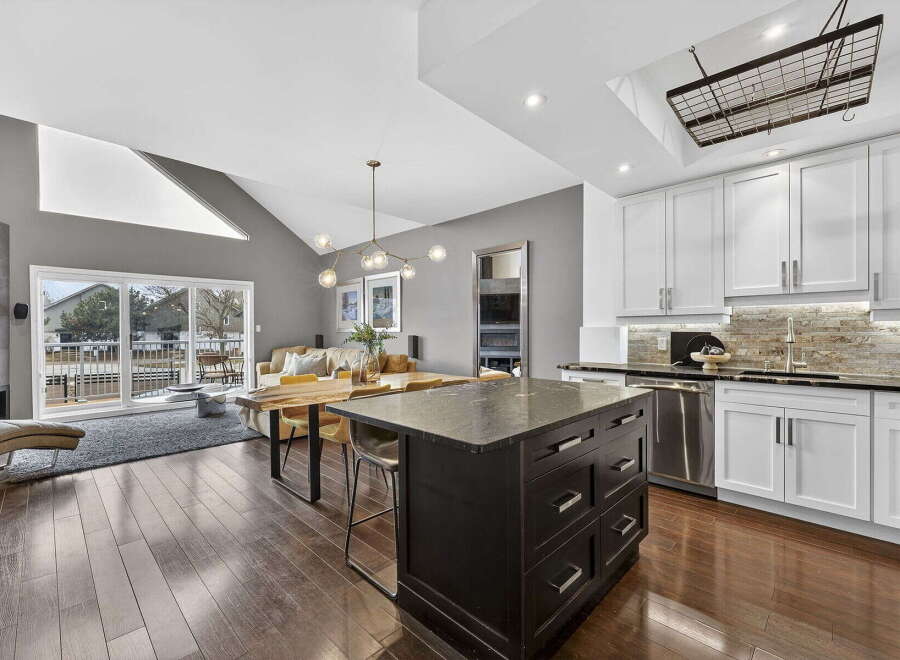 This stunning kitchen boasts a modern design with sleek white cabinetry, stainless steel appliances, and a dark granite island.