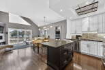 This stunning kitchen boasts a modern design with sleek white cabinetry, stainless steel appliances, and a dark granite island.
