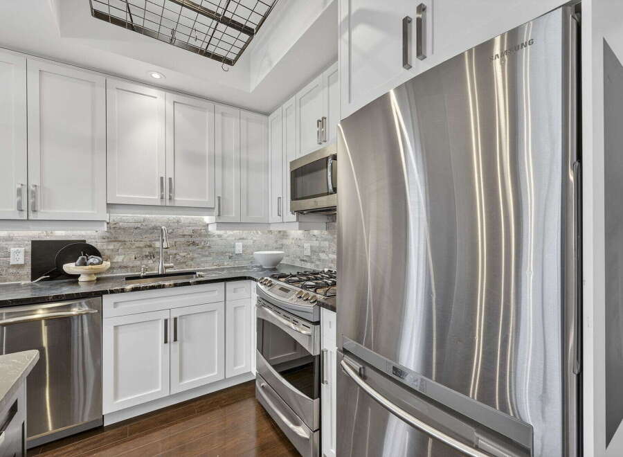 Step into this stunning kitchen, boasting sleek stainless steel appliances and pristine white cabinetry.