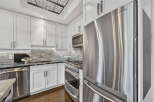 Step into this stunning kitchen, boasting sleek stainless steel appliances and pristine white cabinetry.