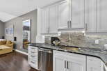 This stunning kitchen boasts sleek white cabinetry, a modern stainless steel dishwasher, and a beautiful granite countertop.