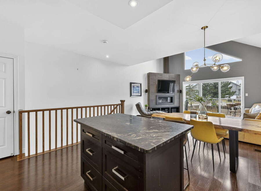 This stunning property boasts a modern kitchen with a sleek island and dark cabinetry, perfect for culinary enthusiasts.