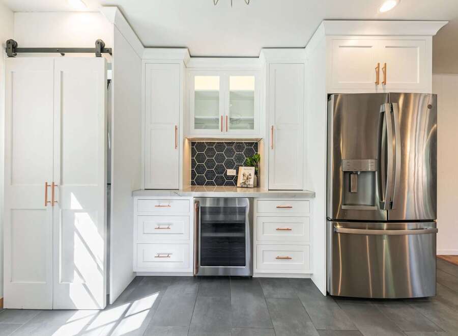 This stunning kitchen boasts a modern design with sleek white cabinetry and elegant copper hardware.