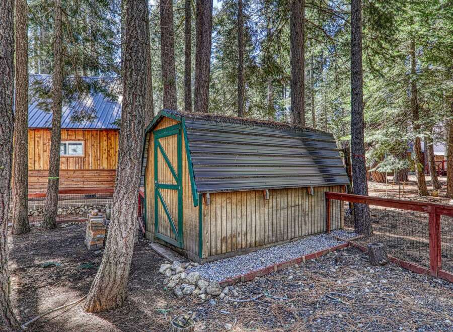 Nestled in a serene wooded setting, this property offers a charming shed with a metal roof, perfect for storage or a workshop.