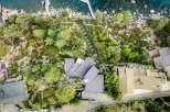 Experience luxury living with this stunning aerial view of a modern architectural masterpiece nestled amidst lush greenery and overlooking crystal-clear waters.
