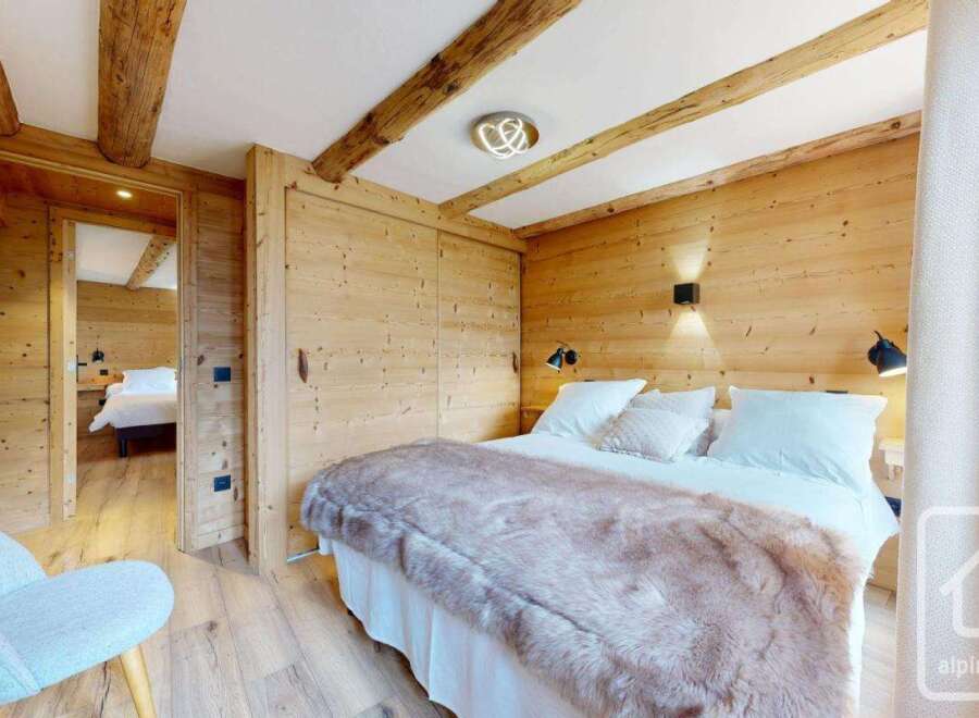 Experience the charm of this stunning property, featuring a cozy bedroom with wooden accents and a plush bed.