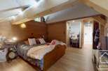 Discover the charm of this cozy bedroom, featuring a warm wooden interior and a comfortable bed.
