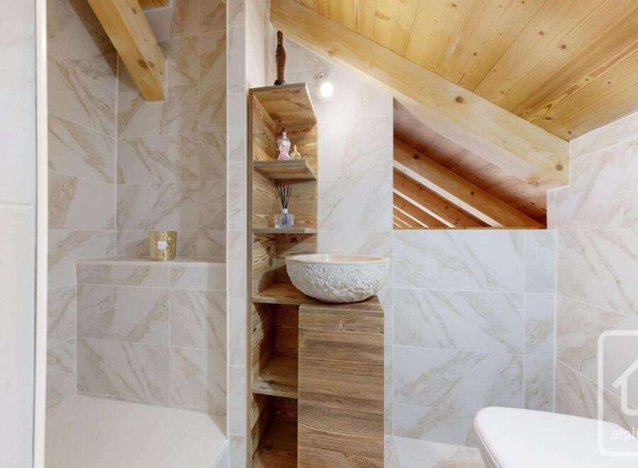 Discover the charm of this unique bathroom design, featuring a rustic wooden vanity and a stylish stone sink.