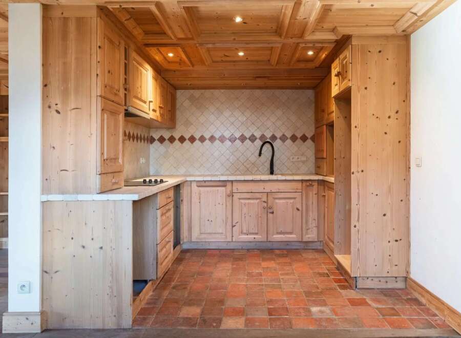 This charming kitchen features a rustic design with wooden cabinets and a terracotta tile floor, creating a warm and inviting atmosphere.