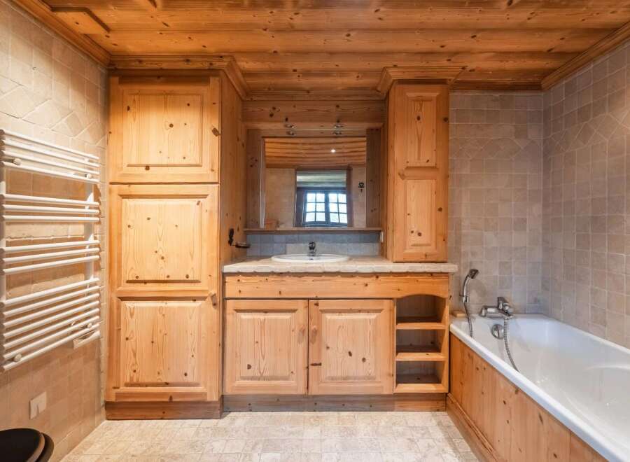 This stunning bathroom boasts a warm and inviting ambiance with its natural wood elements and tiled walls.