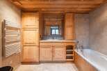 This stunning bathroom boasts a warm and inviting ambiance with its natural wood elements and tiled walls.