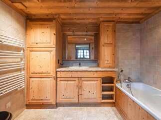 This stunning bathroom boasts a warm and inviting ambiance with its natural wood elements and tiled walls.