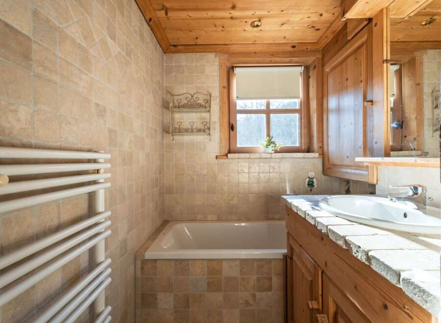This charming bathroom features a warm, inviting ambiance with its wooden accents and neutral-toned tiles.
