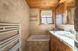 This charming bathroom features a warm, inviting ambiance with its wooden accents and neutral-toned tiles.