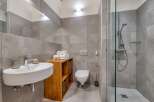 This modern bathroom features a sleek design with gray tiled walls and a glass-enclosed shower.