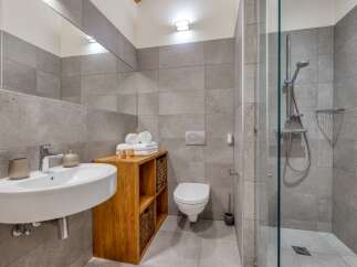 This modern bathroom features a sleek design with gray tiled walls and a glass-enclosed shower.