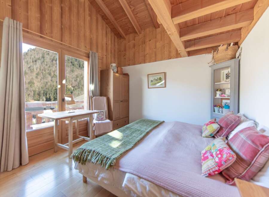 This charming bedroom boasts a cozy ambiance with its wooden walls and ceiling, creating a warm and inviting atmosphere.