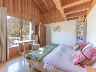 This charming bedroom boasts a cozy ambiance with its wooden walls and ceiling, creating a warm and inviting atmosphere.