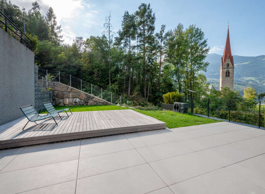 Experience modern outdoor living with this stunning property featuring a spacious wooden deck and a sleek, minimalist patio perfect for entertaining.