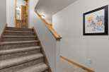 This inviting staircase leads to a cozy interior, featuring warm wooden accents and plush carpeting.