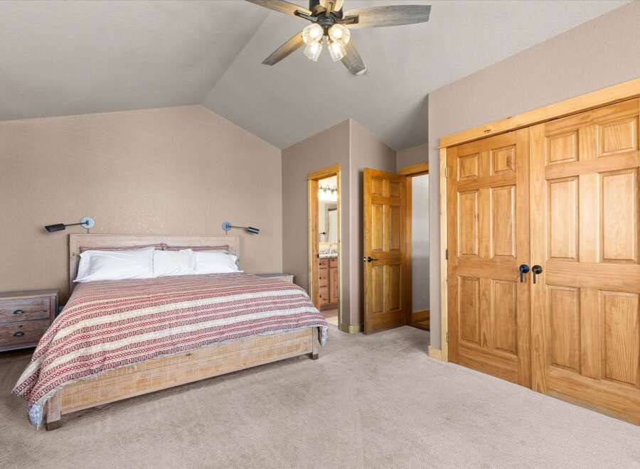 This inviting bedroom showcases a rustic wooden bed frame, complemented by a cozy red and white striped blanket.