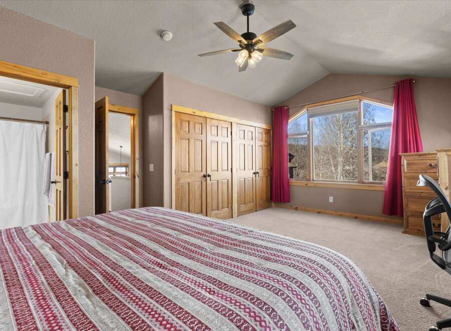 This spacious bedroom boasts a cozy ambiance with its neutral color palette and ample natural light.