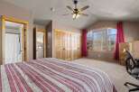 This spacious bedroom boasts a cozy ambiance with its neutral color palette and ample natural light.