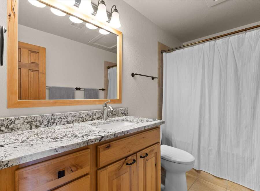 This stunning bathroom boasts a beautiful wooden vanity with a granite countertop, offering both style and functionality.