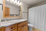 This stunning bathroom boasts a beautiful wooden vanity with a granite countertop, offering both style and functionality.