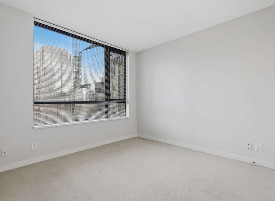 This bright and airy room features a large window with blinds, offering stunning city views and ample natural light.