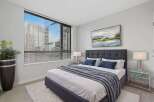 Experience luxury living in this stunning bedroom! Featuring a modern design with a plush bed, a large window with blinds, and a stylish rug.