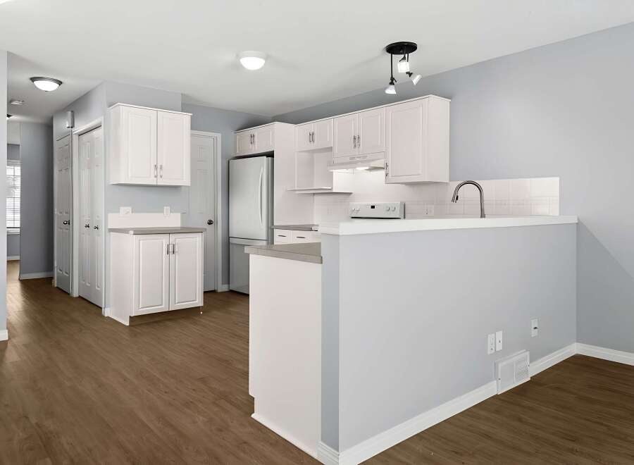 Step into this bright and airy kitchen, featuring modern white cabinetry and sleek countertops.