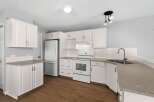Step into this bright and airy kitchen, featuring pristine white cabinetry and sleek countertops.