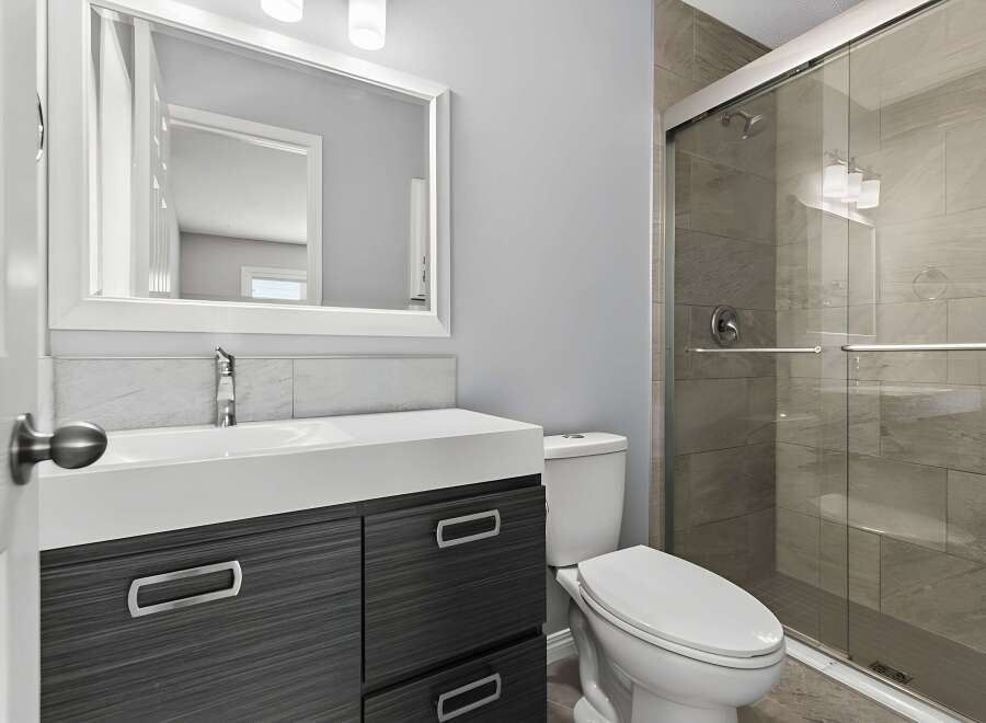 This modern bathroom features a sleek design with a spacious shower and a stylish vanity.