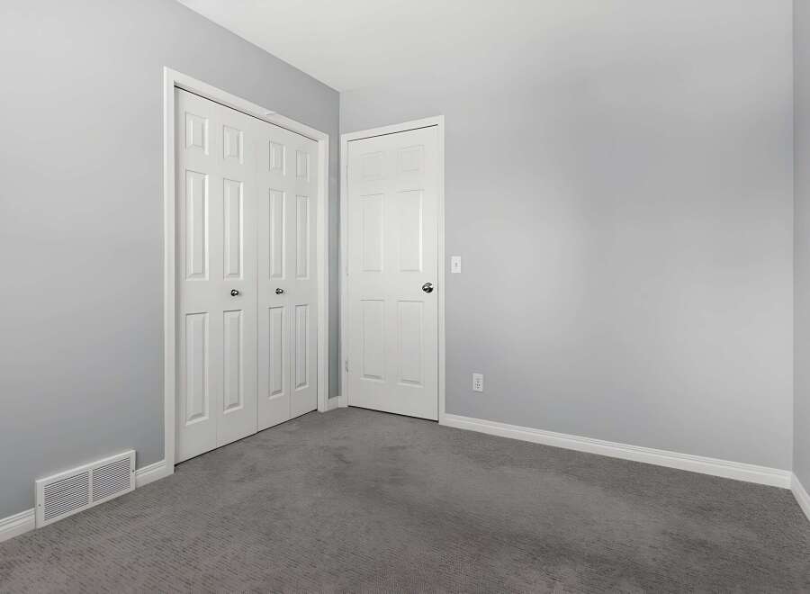 Discover the potential of this inviting space! This room features two white doors, offering ample storage and a clean aesthetic.