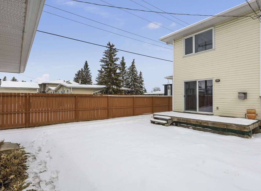 Enjoy the winter wonderland in this charming property! This home features a spacious backyard covered in snow, perfect for outdoor activities.