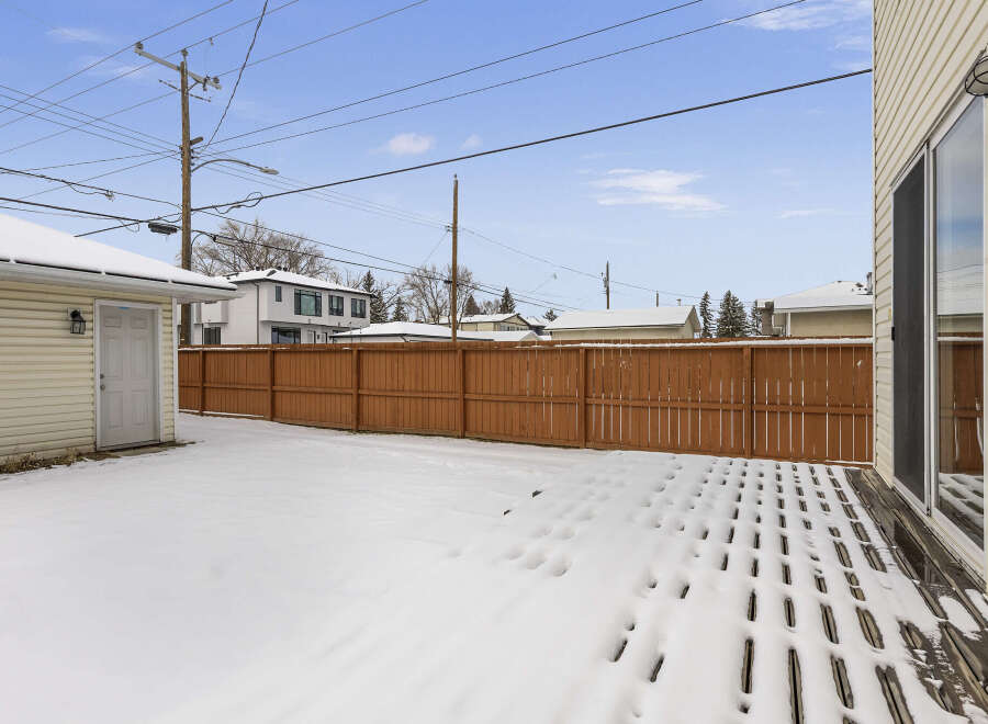 Enjoy the winter wonderland in this charming property! This home features a spacious backyard with a wooden fence, perfect for privacy and outdoor activities.