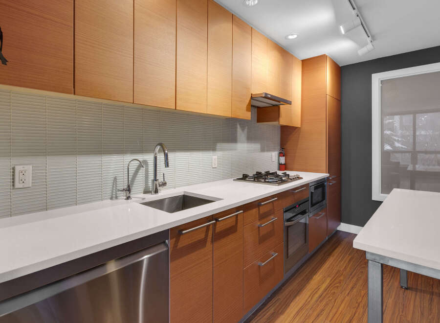 This modern kitchen boasts sleek, wooden cabinetry and a pristine white countertop, creating a stylish and functional space.