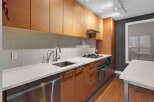 This modern kitchen boasts sleek, wooden cabinetry and a pristine white countertop, creating a stylish and functional space.