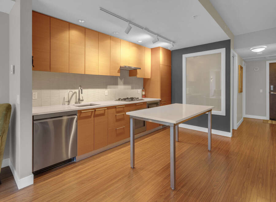 This modern kitchen boasts sleek wooden cabinetry, stainless steel appliances, and a pristine white countertop.