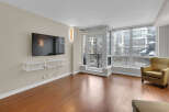 Experience modern living in this stunning condo featuring a spacious living area with a large flat-screen TV and a sleek, floating shelf.