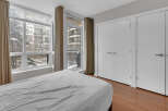 This bright and airy bedroom features a large window with a view of the surrounding neighborhood.