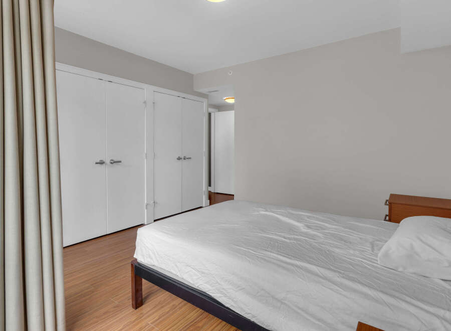 This bedroom offers a serene retreat with its neutral color palette and ample natural light.