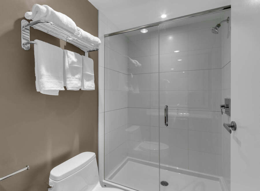 Step into a modern bathroom oasis! This image showcases a sleek, tiled shower with a glass door, perfect for a refreshing start to your day.