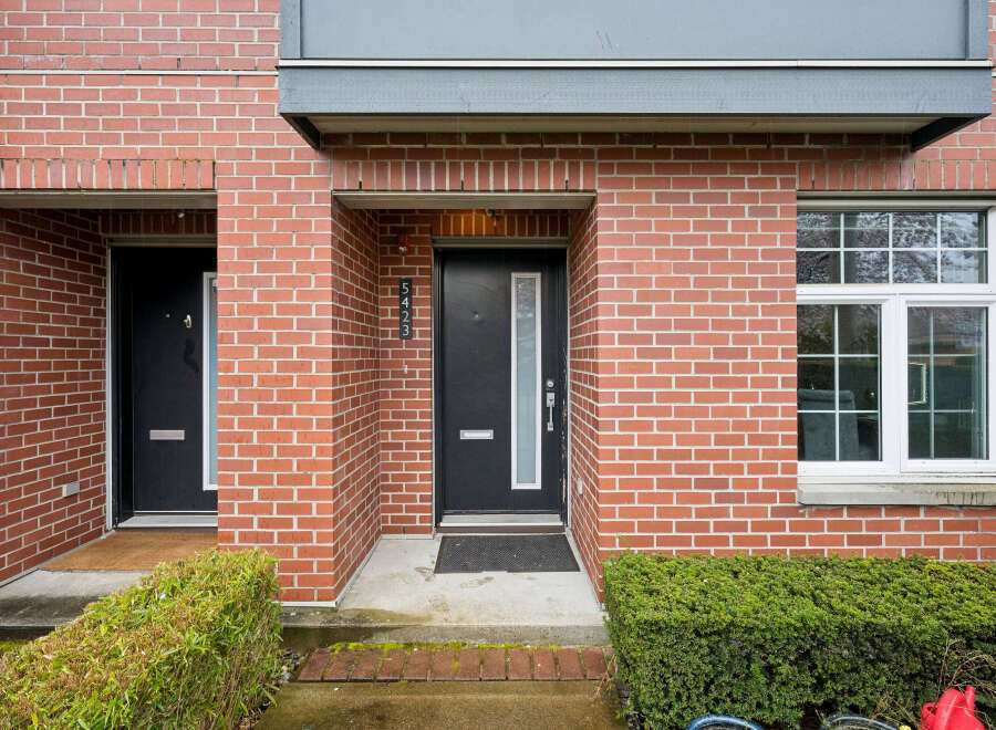 This stunning brick townhouse offers a modern facade with a sleek black door and a welcoming entrance.