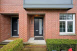 This stunning brick townhouse offers a modern facade with a sleek black door and a welcoming entrance.