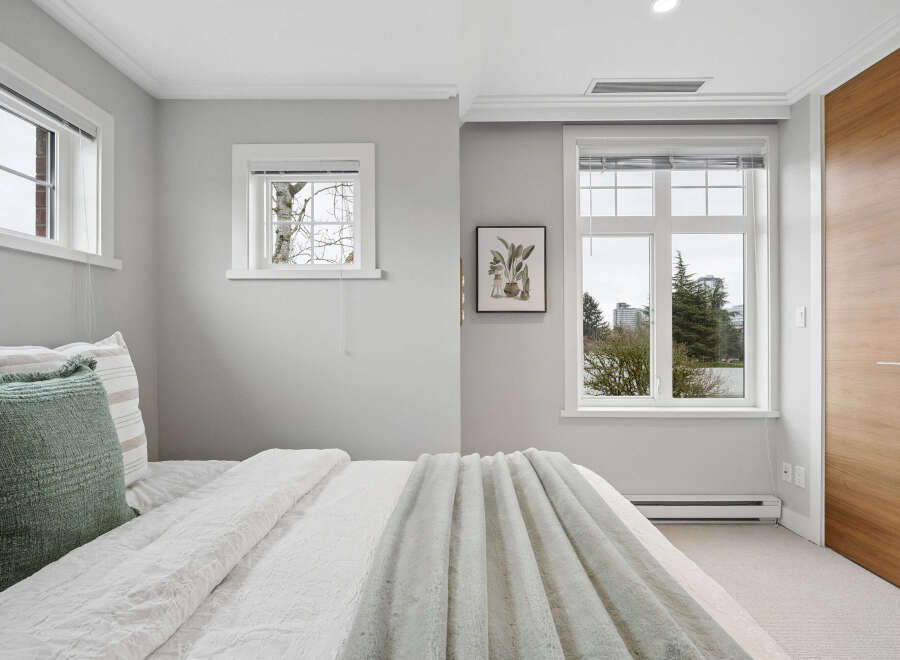 This bedroom offers a serene retreat with its neutral color palette and ample natural light.