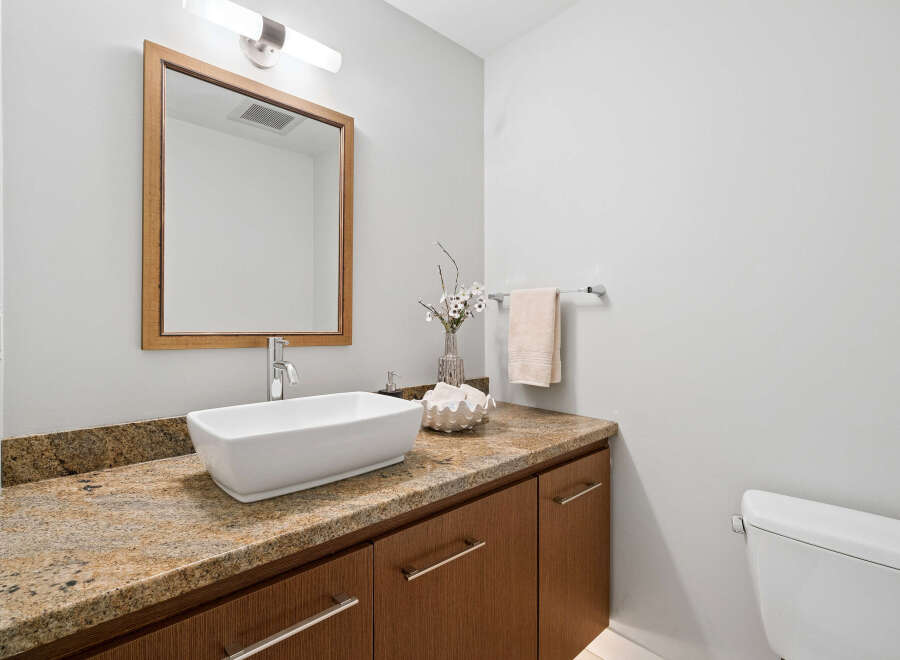 This stunning bathroom features a modern design with a sleek white sink and a beautiful granite countertop.