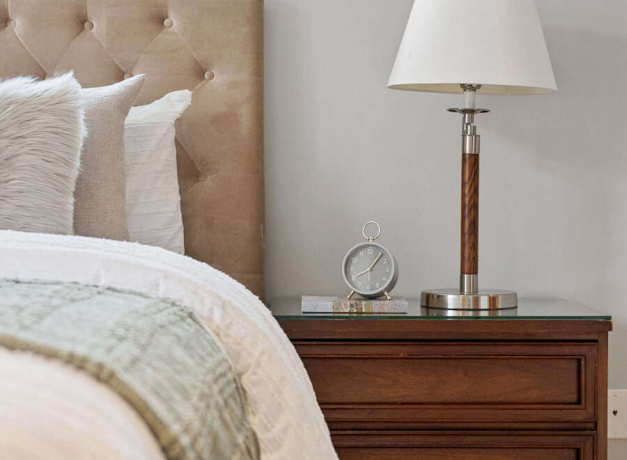 This cozy bedroom features a tufted headboard, a stylish nightstand, and a classic lamp.