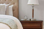 This cozy bedroom features a tufted headboard, a stylish nightstand, and a classic lamp.